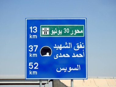 Suez, Egypt, August 12 2022: a road sign board in Suez Cairo highway in Arabic, Translation (June 30th Axis 13 KM, Martyr Ahmed Hamdi Tunnel 37 KM, Suez 52 KM), selective focus of a road sign