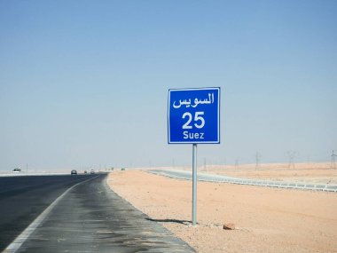 Suez, Egypt, August 12 2022: a road sign board in Suez Cairo highway gives the remaining distance to Suez city 25 KM twenty five kilometers written in Arabic and English at the side of the street
