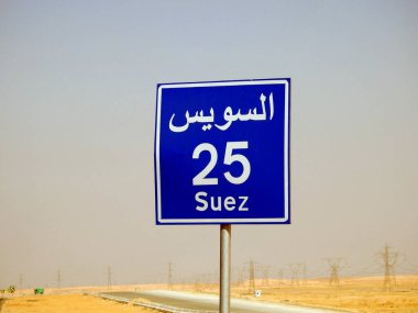 Suez, Egypt, August 12 2022: a road sign board in Suez Cairo highway gives the remaining distance to Suez city 25 KM twenty five kilometers written in Arabic and English at the side of the street