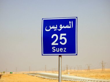 Suez, Egypt, August 12 2022: a road sign board in Suez Cairo highway gives the remaining distance to Suez city 25 KM twenty five kilometers written in Arabic and English at the side of the street