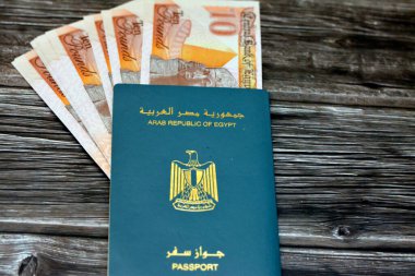 Egyptian passport with new polymer 10 EGP LE ten Egyptian pounds money banknotes isolated on wooden background, Arab republic of Egypt's passport with the republican golden eagle and Egypt money