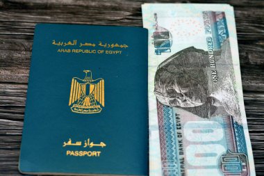 Egyptian passport with 100 EGP LE one hundred Egyptian pounds money banknotes isolated on wooden background, Arab republic of Egypt's passport with the republican golden eagle and Egypt money