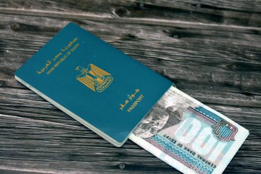 Egyptian passport with 100 EGP LE one hundred Egyptian pounds money banknotes isolated on wooden background, Arab republic of Egypt's passport with the republican golden eagle and Egypt money