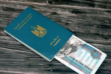 Egyptian passport with 100 EGP LE one hundred Egyptian pounds money banknotes isolated on wooden background, Arab republic of Egypt's passport with the republican golden eagle and Egypt money