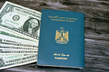 Egyptian passport with American dollars of 1 $ one United states money banknotes isolated on wooden background, Arab republic of Egypt's passport with the republican golden eagle and American money