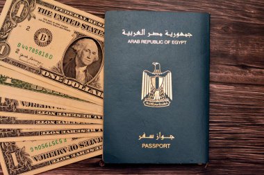 Egyptian passport with American dollars of 1 $ one United states money banknotes isolated on wooden background, Arab republic of Egypt's passport with the republican golden eagle and American money