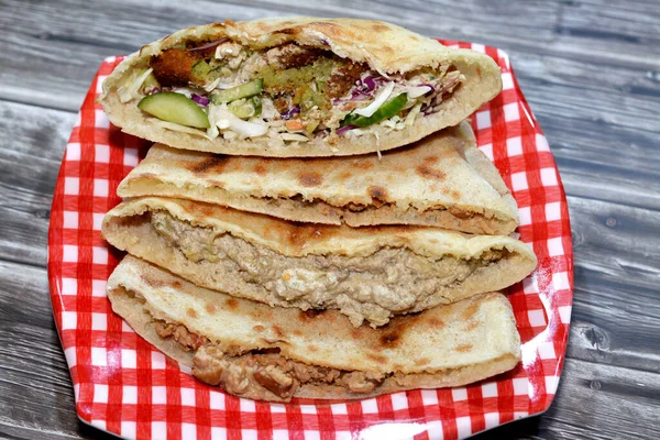 Traditional Egyptian popular breakfast street sandwiches of mashed fava beans, fried crispy falafel balls and baba ghanoush aubergine roast in flat bread, selective focus of famous cuisine in Egypt