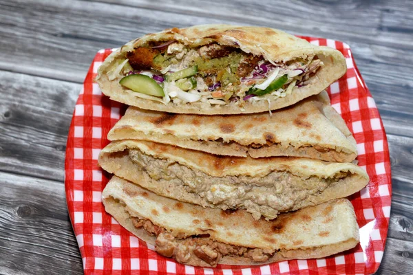 Traditional Egyptian popular breakfast street sandwiches of mashed fava beans, fried crispy falafel balls and baba ghanoush aubergine roast in flat bread, selective focus of famous cuisine in Egypt