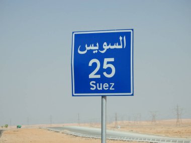 Suez, Egypt, August 12 2022: a road sign board in Suez Cairo highway gives the remaining distance to Suez city 25 KM twenty five kilometers written in Arabic and English at the side of the street