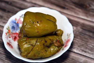 A plate of filled bell peppers stuffed Egyptian mahshi and filled with white rice, onion, parsley, dill and coriander, selective focus of Arabic Egyptian traditional cuisine of Mahshy isolated on wood