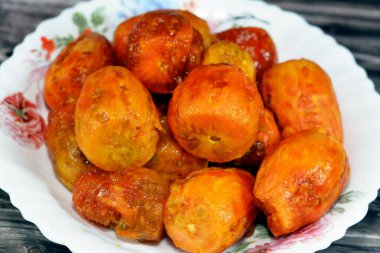 Ahşap arka planda izole edilmiş beyaz bir tabakta soyulmuş taze dikenli armut yığını, seçici odaklanma, Opuntia, genellikle dikenli armut, berber inciri, ton balığı, sabra ve nopal olarak adlandırılır.