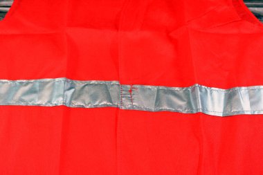 Ahşap arka planda yansıtıcı çizgili kırmızı yansıtıcı güvenlik yeleği, inşaat işleri için açık yelek, sürücüler, yol işçileri ve floresan şeritli itfaiyeciler.