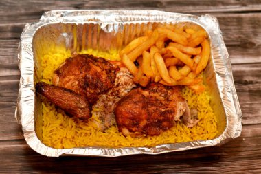 Arap mutfağında ızgara tavuk, sarı Basmati pilavı ve patates kızartması, ahşap arka planda izole edilmiş folyo tabakta servis edilen kızarmış patates.