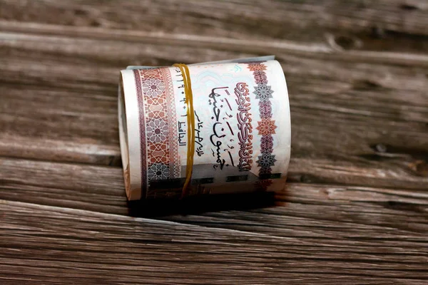 Egypt money roll pounds isolated on wooden background, 50 LE fifty Egyptian pounds cash money bills rolled up with rubber bands with a image of Abu Hurayba Mosque, temple of Edfu and winged scarab