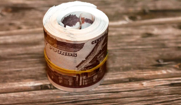 Egypt money roll pounds isolated on wooden background, 50 LE fifty Egyptian pounds cash money bills rolled up with rubber bands with a image of Abu Hurayba Mosque, temple of Edfu and winged scarab