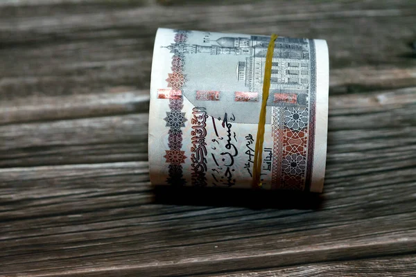 Egypt money roll pounds isolated on wooden background, 50 LE fifty Egyptian pounds cash money bills rolled up with rubber bands with a image of Abu Hurayba Mosque, temple of Edfu and winged scarab