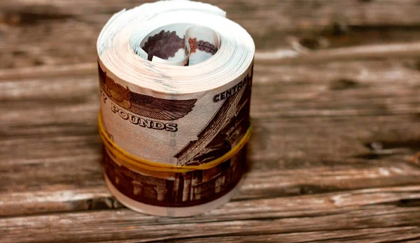 Egypt money roll pounds isolated on wooden background, 50 LE fifty Egyptian pounds cash money bills rolled up with rubber bands with a image of Abu Hurayba Mosque, temple of Edfu and winged scarab