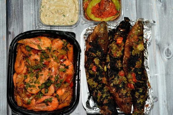 Seafood cuisine of Boiled shrimps mixed garlic, lemon, parsley, pepper, onion and tomato and Charcoal grilled barbecued mullet fish with parsley and tomato with tahini sauce and pickled eggplant