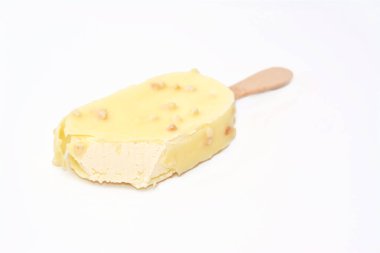 Vanilyalı dondurma çubuğu kaplanmış ve fındıklı beyaz çikolata tabakasıyla kaplanmış, beyaz çikolatalı ve kavrulmuş badem ve fındıklı zengin vanilyalı dondurma, seçici odaklı.