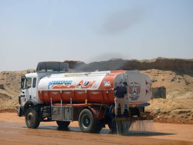 Giza, Mısır, 25 Temmuz 2022: Mısır gayrimenkul projelerinde yeni yollar yapmak için asfalt emülsiyon yapmadan önce yol döşeme işlemi sırasında su sağlamak için bir nakliye su tankı aracı