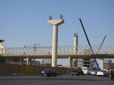 Giza, Mısır, 25 Temmuz 2022: Giza Mısır üstten taşıma sistemi demiryolu inşaat sahasında beton ve çelik kolonlar ve vinçler ile 6 Ekim 'de eksen yolunda