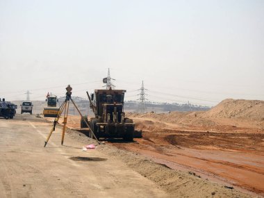 Giza, Mısır, 25 Temmuz 2022: Mısır 'daki emlak projelerinde yeni yolların inşasında asfalt emülsiyonu yapılmadan önce asfalt döşeme sürecinde yer aşamalı kamyon ve lazer düzleştirici ile düzleştiriliyor
