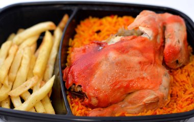 Uzun basmati pilavlı tavuk mandi ve patates kızartması, domates soslu, Yemen usulü, baharatlı ve soslu Mandi tavuğu tarifinin seçici odak noktası.