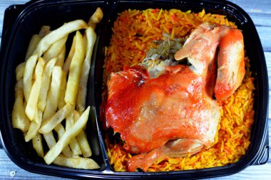 Uzun basmati pilavlı tavuk mandi ve patates kızartması, domates soslu, Yemen usulü, baharatlı ve soslu Mandi tavuğu tarifinin seçici odak noktası.