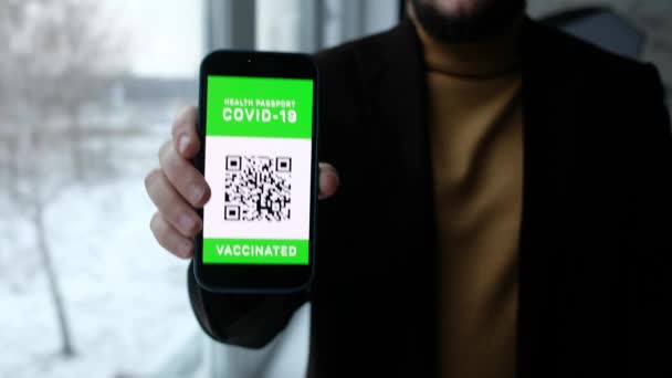 Man menunjuk ke ponsel kamera dengan paspor digital Imune untuk covid-19 di bandara. Smartphone dengan kode qr di tangan. — Stok Video