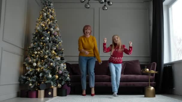 Счастливые мать и дочь танцуют и веселятся в гостиной дома Рождественские каникулы. — стоковое видео