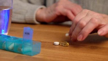 Yaşlı kadın her gün hap ve vitamin alıyor. Emekli olan ilaç kapsülünü alır ve suyla içer..