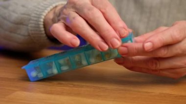 Yaşlı kadın ilaç kutusunu açar, bir omega 3 kapsülü alır ve içer..