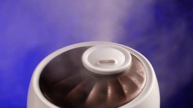 Nemlendirici mavi arka planda buhar oluşturur. Çalışan hava temizleyiciden buhar çıkıyor..