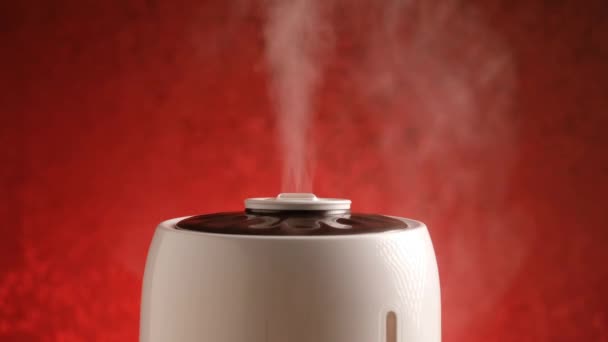 加湿器は赤い背景に蒸気を発生させる。蒸気清浄機. — ストック動画