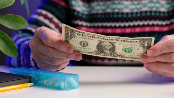 Äldre kvinna har sedlar med pengar sittandes vid bordet hemma. Begreppet pengar tillbaka från inköp, köp av läkemedel, betalning för behandling. — Stockvideo