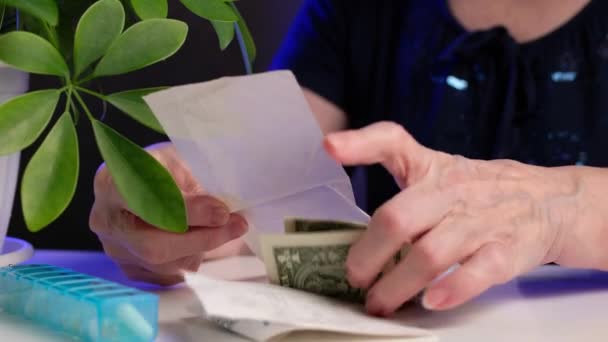 Starší žena kontroluje účtenku a počítá nákupy u stolu doma. Vzestup cen léčivých přípravků. — Stock video
