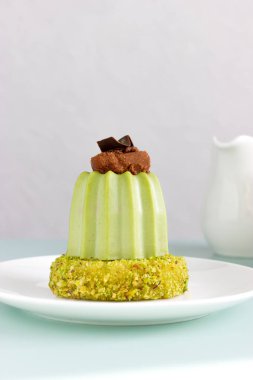 Şam fıstıklı kremalı tatlı, fıstıklı browni beyaz tabakta hafif arkaplan, üstünde çikolata olan tatlı, fotokopi alanı. Dikey düzlem