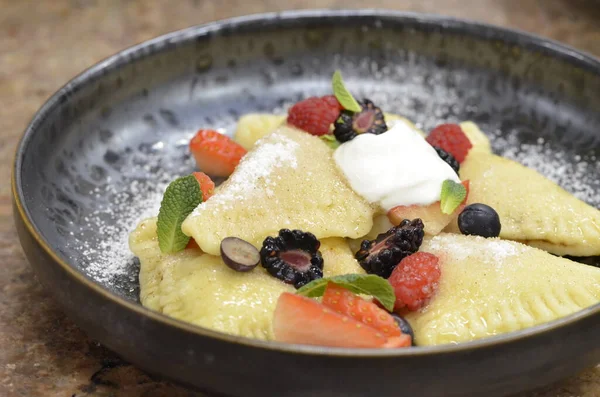 crepes with fresh strawberries, cream and blueberries on a black background. close - up.