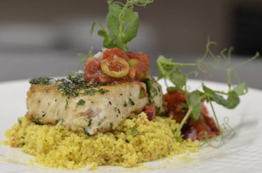 Beyaz tabakta sebzeli balık.