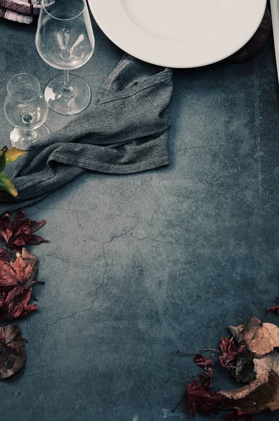 Ahşap arka planda sonbahar yaprakları ve şarap kadehleri.