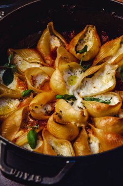 Fesleğen ve krem peynirle doldurulmuş makarna kabukları doğranmış fesleğen yaprakları serpiştirilmiş domates sosu, üst manzara.