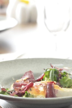 Kavrulmuş keçi peynirli pancar kökü salatası ve kırsal bir restoranın arka planındaki bir restorandaki ahşap masaya dayanan otlar.