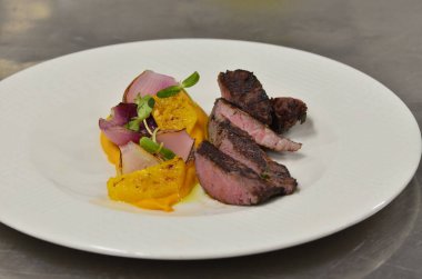 Orta boy biftek fileto, meze, sebze, restoranda beyaz tabakta servis edilen yemekler.