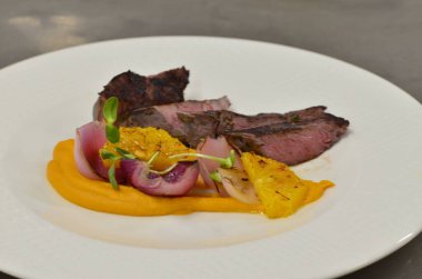 Orta boy biftek fileto, meze, sebze, restoranda beyaz tabakta servis edilen yemekler.