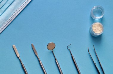 Masada dişçi aletleri, diş tedavisi için hazırlıklar ve covid-19 için gereken yüz maskesi bulunuyor.