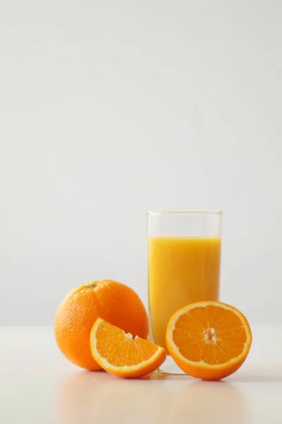 ジューシーなオレンジから絞りたてのオレンジジュースのガラス 全体のオレンジ 半分と4分の1テーブルの上にあります 一日の良いスタート エネルギーと活力のブースト ビタミンCと濃縮 優れた朝食 — ストック写真
