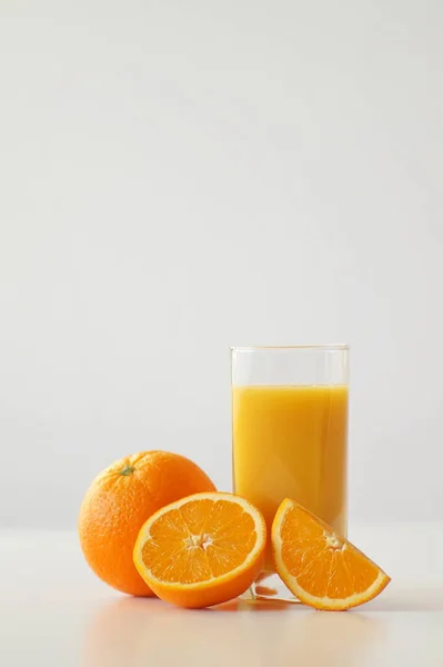 絞りたてのオレンジジュースのガラスの横にオレンジの全体のオレンジ 半分と4分の1が横たわっています ビタミンC エネルギー 陽気さとその日の良いスタート 朝食への追加です — ストック写真