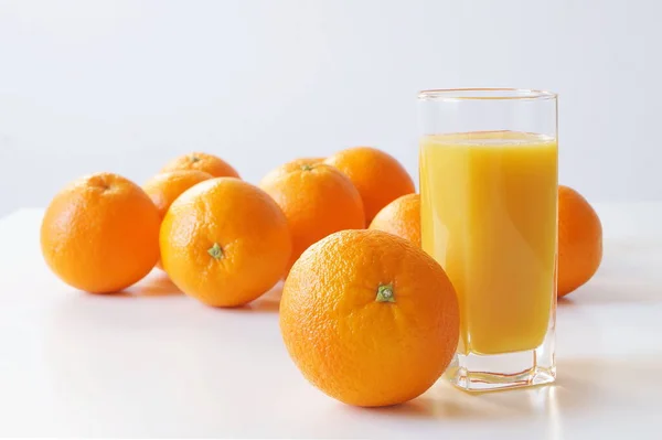 オレンジはテーブルの上にあり テーブルの上には 朝食のための新鮮な絞り汁のガラスであり 一日の良いスタートであり ビタミンCで体を豊かに — ストック写真