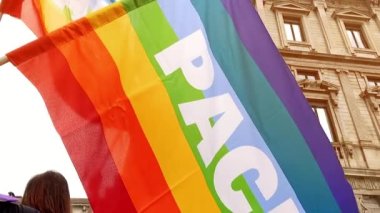 Barış dolu gökkuşağı bayraklı insanlar barış gösterisinde yavaş çekimde sallanıyorlar ve Rusya-Ukrayna savaşına karşılar. Faşizmden kurtuluşun İtalyan yıldönümü