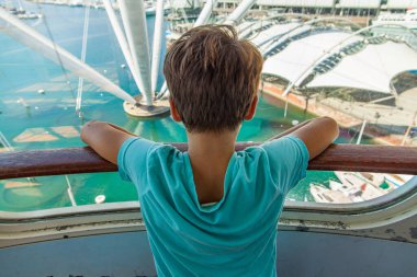 Küçük bir çocuk Cenova 'nın antik limanının vinç kaldırışından (porto Antico) deniz manzarasının panoramik manzarasına bakar limana demirlemiş teknelerle birlikte.